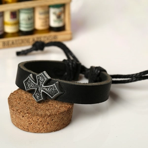 Bracelet vintage en cuir noir pour homme avec croix en métal sur fond de liège rustique
