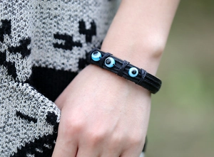 Détail d'un bracelet en cuir ethnique avec trois perles œil bleu sur un poignet