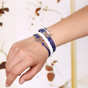 Multilayer braided nautical bracelet with anchor and helm charms on woman's wrist