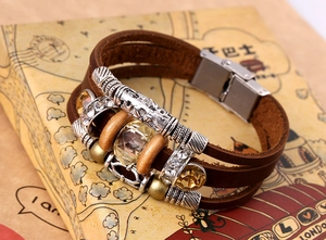 Dettaglio bracciale in pelle multistrato con perline metalliche su scatola vintage