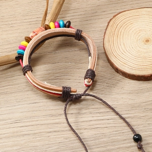 Macro shot of bohemian woven leather bracelet with colorful wood beads and adjustable knot