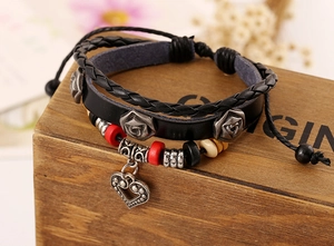 Détail d'un bracelet multicouche en cuir avec perles et breloque cœur sur boîte en bois