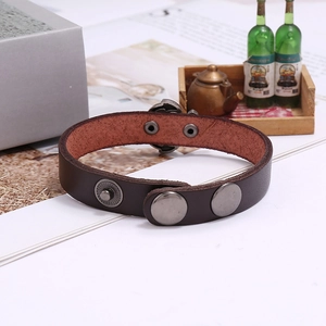 Detail of dark brown leather punk bracelet with silver skull studs and adjustable snaps