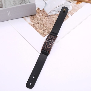 Détail d'un bracelet en cuir noir vintage avec plaque en bronze à nœud celtique et rivet rond