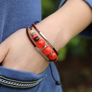 Bohemian multi-layer leather bracelet with red beads and metal accents on a female wrist