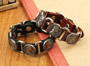 Détail de bracelets en cuir vintage avec anneaux métalliques et pièces Elizabeth II