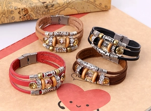 Dettaglio di bracciali bohémien multistrato in pelle con perline in legno e ciondoli in metallo