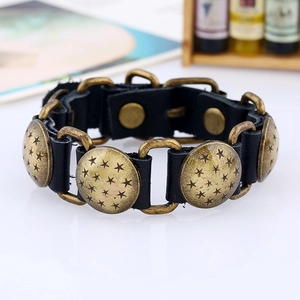 Dettaglio di bracciale punk in pelle con placche di bronzo incise a stella e bottoni
