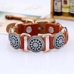 Macro detail of brown leather bracelet with silver sunburst studs and metal snap closure