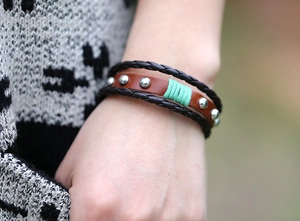 Gros plan du bracelet multicouche en cuir vintage avec rivets argentés et fil turquoise