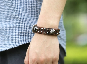 Gros plan d'un bracelet punk en cuir marron vintage avec rivets et clous en forme de soleil