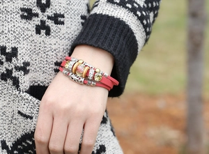 Dettaglio del bracciale multistrato in pelle rossa con perle boho e ciondoli in lega