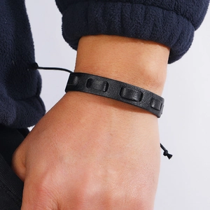 Close-up of black braided leather bracelet with rectangular cutouts on a wrist