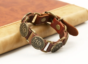 Detail of vintage leather bracelet with antique 1990 coins and rustic bronze links