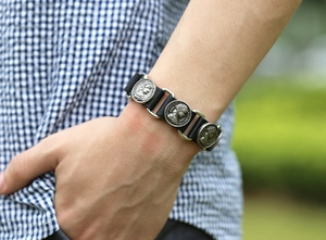 Gros plan d'un bracelet en cuir vintage avec breloques pièces métalliques et buste de reine