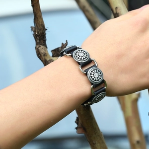 Detail of vintage leather bracelet featuring three engraved silver sunburst metal charms