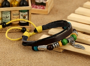 Detail of bohemian multilayer leather bracelet with feather pendant and wood beads