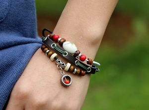Close-up of bohemian multilayer leather bracelet with wooden beads and floral ceramic bead