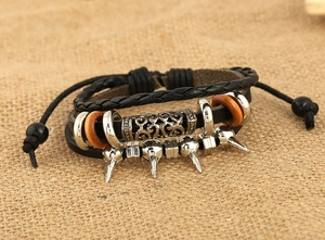 Détail d'un bracelet punk en cuir avec tresses multicouches, anneaux en bois et clous argentés