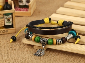 Macro view of multi-layer leather bracelet with wooden beads and leaf metal charm