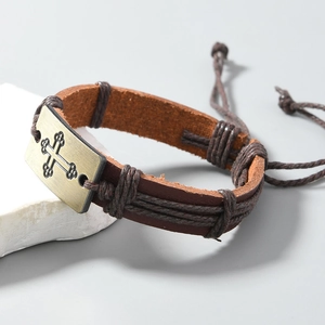 Gros plan d'un bracelet en cuir marron avec pendentif croix en bronze sur une pierre blanche