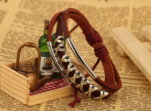 Detail eines Vintage-Lederarmbands in Rotbraun mit silbernem Metallrohr und Kreuzmuster