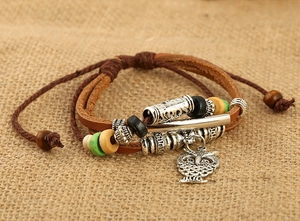 Dettaglio del bracciale multistrato in pelle con ciondolo a civetta e perline di legno