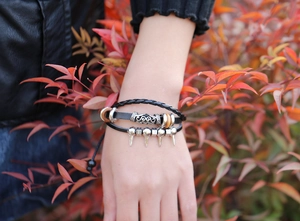 Détail d'un bracelet en cuir multicouche avec pointes punk argentées et perles en bois