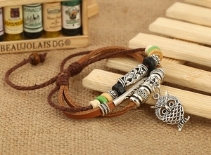 Dettaglio del bracciale multistrato in pelle con ciondolo a civetta e perline in stile retrò