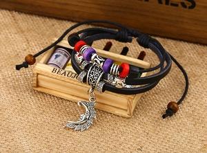 Detail of multilayer leather bracelet with silver moon pendant and vintage wooden beads