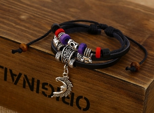 Macro detail of multi-layer leather bracelet with silver crescent moon face charm