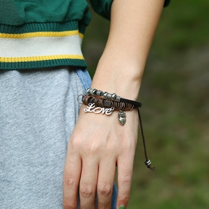Close-up of multilayer leather bracelet with beaded charms and Love pendant detail