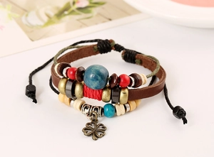 Detail of multilayer leather bracelet with wooden beads and a clover metal charm