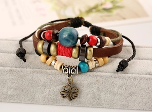 Macro detail of multi-layer leather bracelet with wooden beads and bronze clover charm