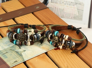 Dettaglio di bracciali multistrato in pelle vintage con teschi e ingranaggi