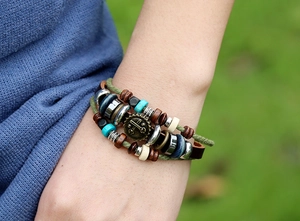 Dettaglio di un bracciale in pelle multistrato con ingranaggio in bronzo e perline