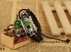 Detail of woven black leather bracelet featuring green thread and metal accents