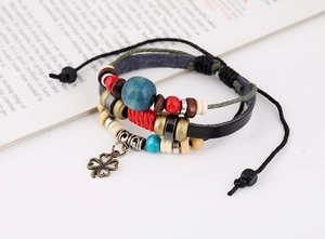 Detail of bohemian multilayer braided leather bracelet with wooden beads and clover charm