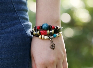 Close-up of multilayer leather bracelet with colorful wooden beads and clover charm
