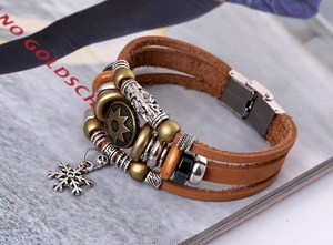 Detail of multilayer leather bracelet with sun totem charm and silver snowflake pendant