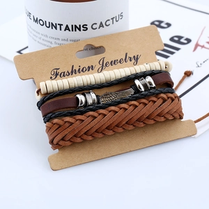 Set of four vintage braided leather bracelets featuring a metal wing charm on a card