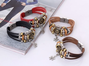 Detail of multilayer leather bracelets with vintage snowflake pendants and metal clasps