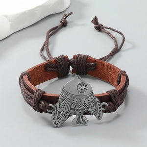 Close-up of vintage braided leather bracelet featuring a fish-shaped metal charm and slider knot