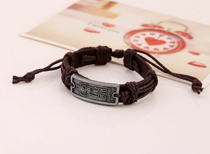Detail of vintage leather bracelet with Sweden engraved metal plate and braided cords