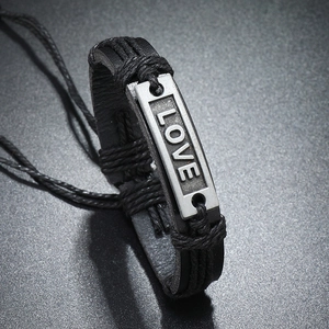Detailed close-up of handmade woven leather bracelet with metal LOVE plaque and braided cords