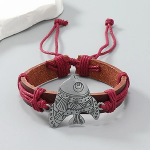 Detail of hand-woven leather bracelet featuring vintage silver fish charm and pull cord