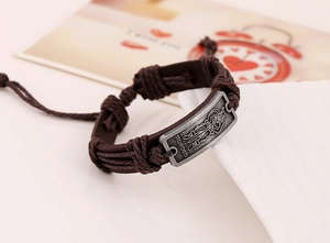 Macro shot of retro leather bracelet with engraved SLENDER metal plate and braided cord