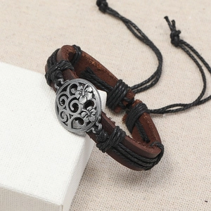 Gros plan du bracelet rétro en cuir marron tressé avec breloque florale en argent
