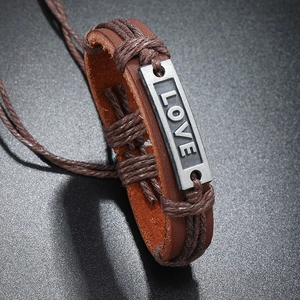 Macro shot of retro dark brown braided leather bracelet with engraved LOVE metal plate