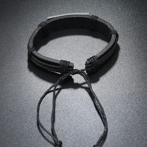 Macro view of woven black leather bracelet with adjustable cords and metal plate